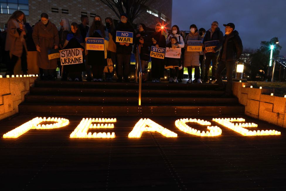 Ucranianos residentes en Japón sostienen pancartas contra la guerra y participan en la vigilia con velas por la paz en el Museo de Historia de Osaka el 24 de febrero de 2023 en Osaka, Japón.