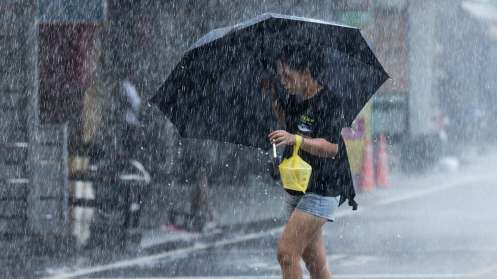 A woman walks with an umbrella during heavy rain as Typhoon Haikui makes landfall in eastern Taiwan