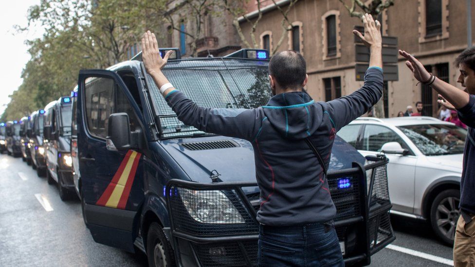 A man blocks a line of police truck as they try to control the area as people wait to cast their ballot in the referendum vote at Escola Industrial of Barcelona school polling station on October 1, 2017 in Barcelona, Spain.