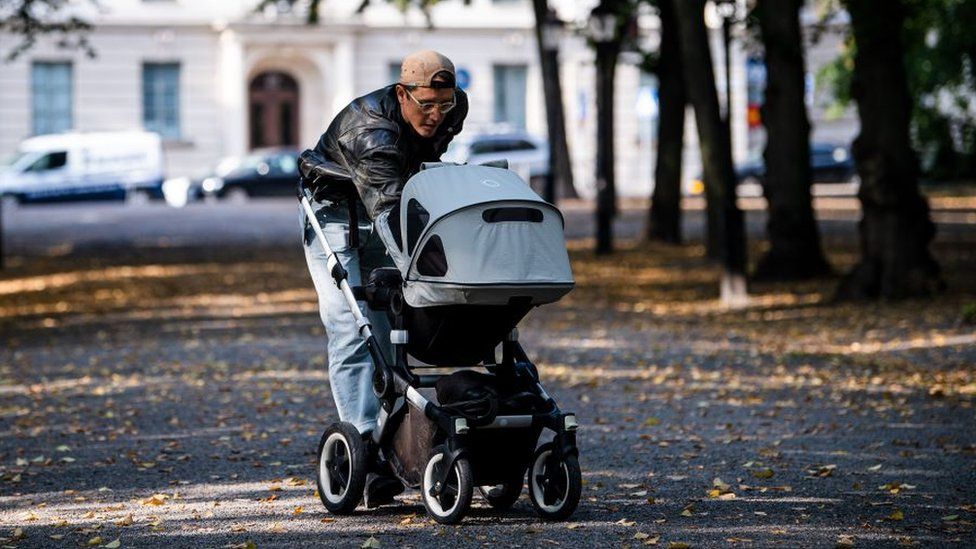 Мужчина выгуливает своего ребенка в детской коляске в Humlegarden в Стокгольме 24 сентября 2020 года.