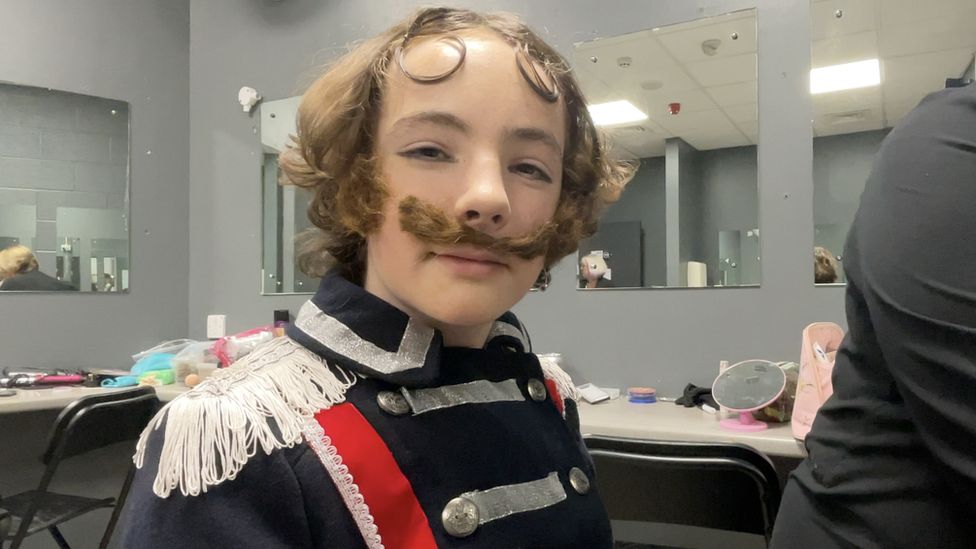 Young actor Bob wearing a fake moustache in regimental clothes and tassels
