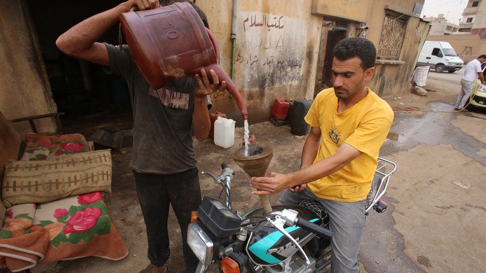 A Syrian man fills a motorbike's tank with locally-extracted and refined fuel at a makeshift refinery in Qamishli, Hassakeh province (15 July 2015)