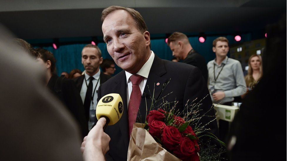 Swedish PM Stefan Lofven talks to the press, carrying red roses, after a TV debate on 7 September 2018