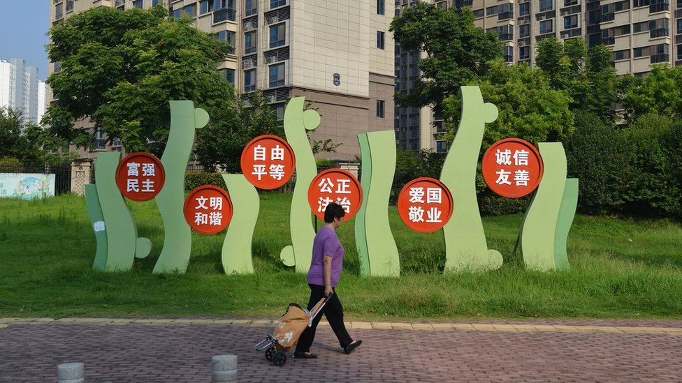 A woman walks past a residential building of Country Garden in Fuyang City in China.