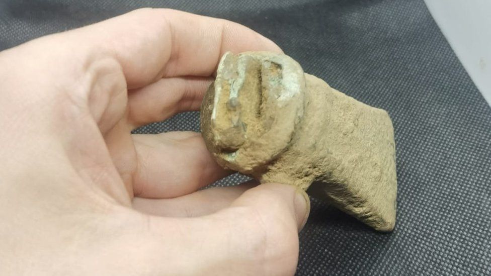 A close up of a hand holding the small axe head