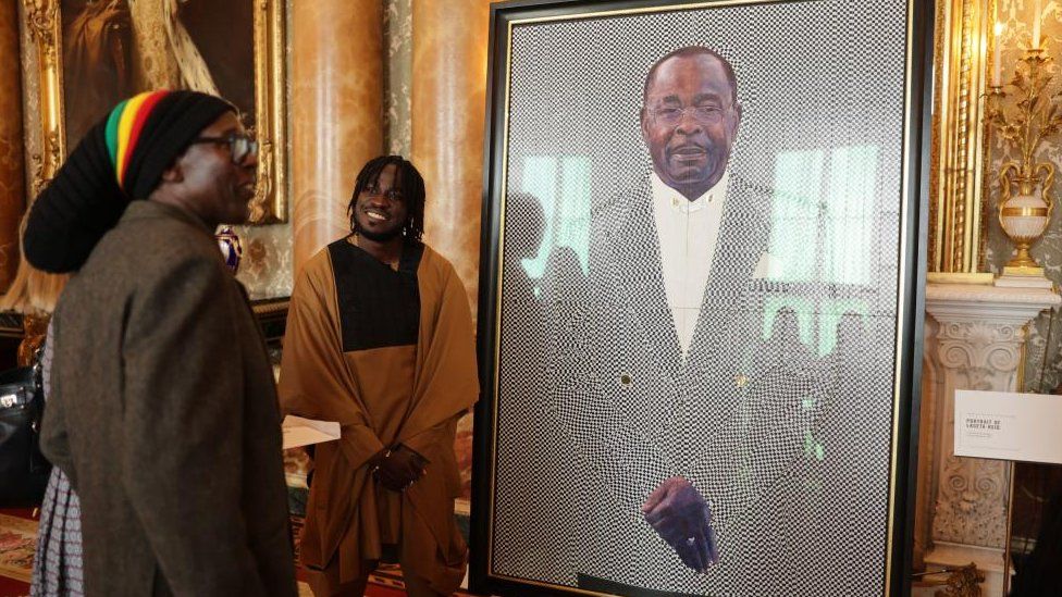 Two men looking at a portrait in Buckingham Palace