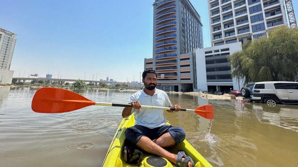 A man in a kayak in floodwater in Dubai