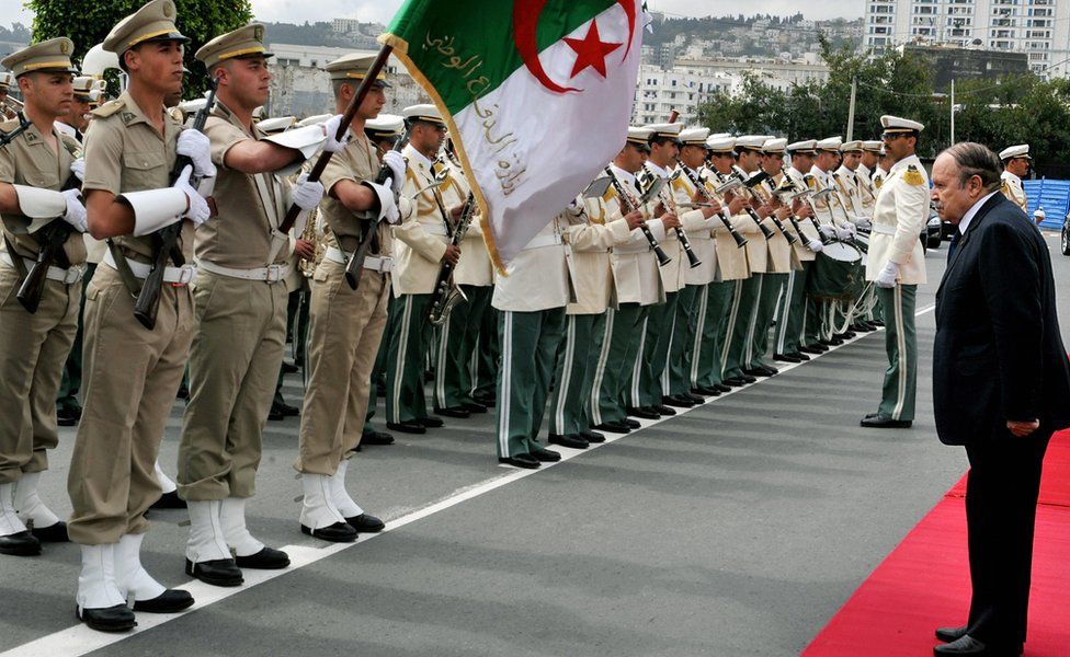 Algerian President Abdelaziz Bouteflika (R) salutes the national flag as he reviews a guard of honour in Algiers - 2009