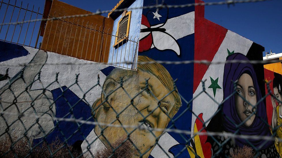 A mural of US President Donald Trump and a young girl in a headscarf in front of a Syrian flag is displayed on the side of a home on January 27, 2017 in Tijuana, Mexico