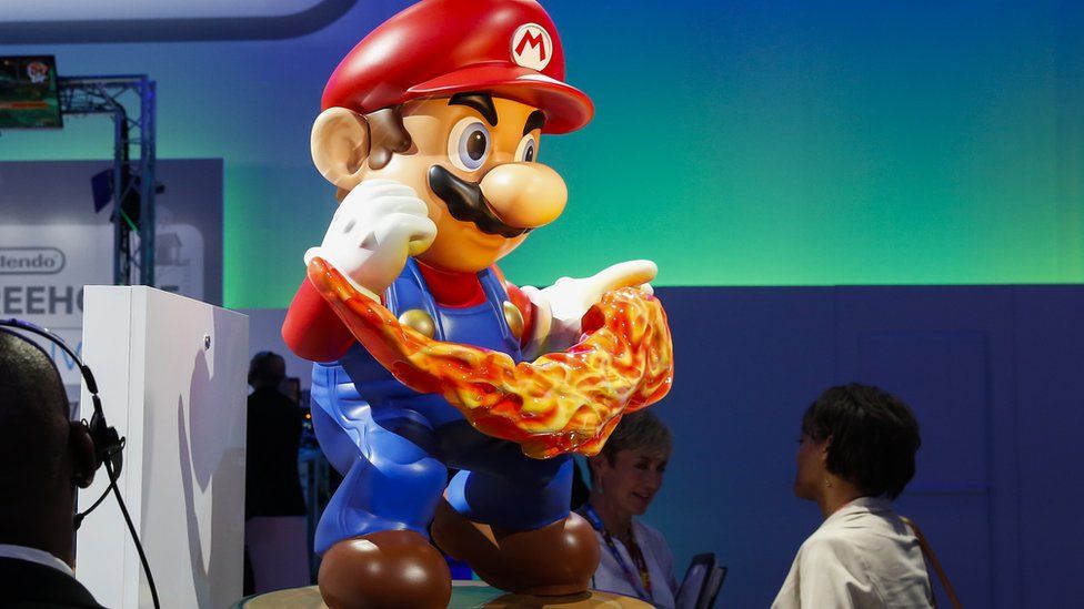 A Super Mario statue with someone looking up at it at E3
