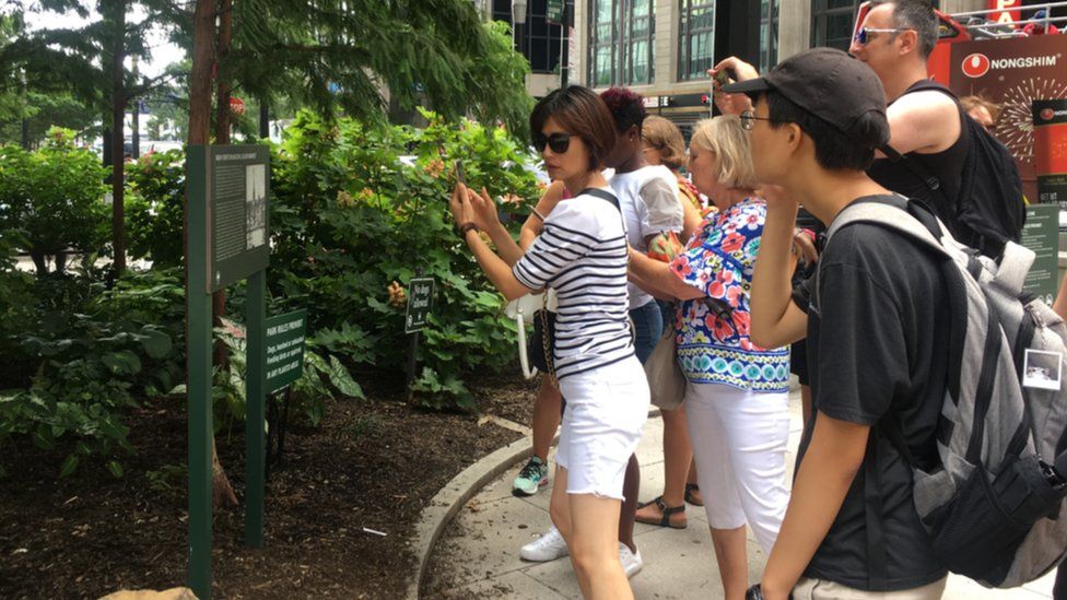 A tour group photographs a sign marking the location of New York City's slave market.