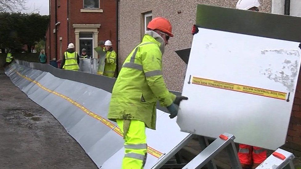 Workers install temporary flood barriers in Billington