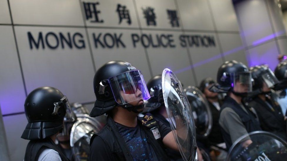 Hong Kong riot police stand guard as anti-government protesters gather outside the Mong Kok Police station