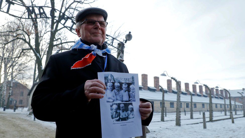 A survivor holds a poster at the former Nazi German concentration and extermination camp Auschwitz, as he attends ceremonies marking the 74th anniversary of the liberation of the camp and International Holocaust Victims Remembrance Day, in Oswiecim, Poland