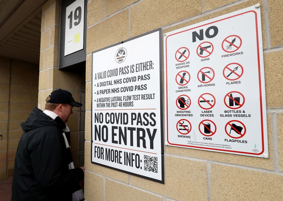 A Swansea City fan entering the stadium next to a sign stating a Covid pass is required to enter the stadium before the Sky Bet Championship match, on 22 January 2022