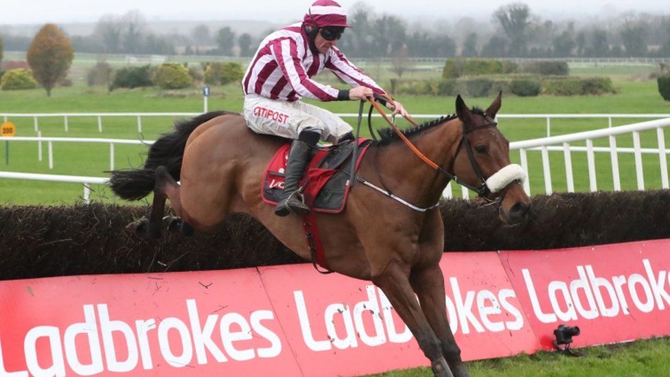 Race horse jumping over Ladbrokes sponsored fence