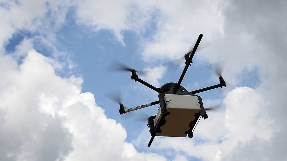 A drone carrying a parcel is seen in the sky