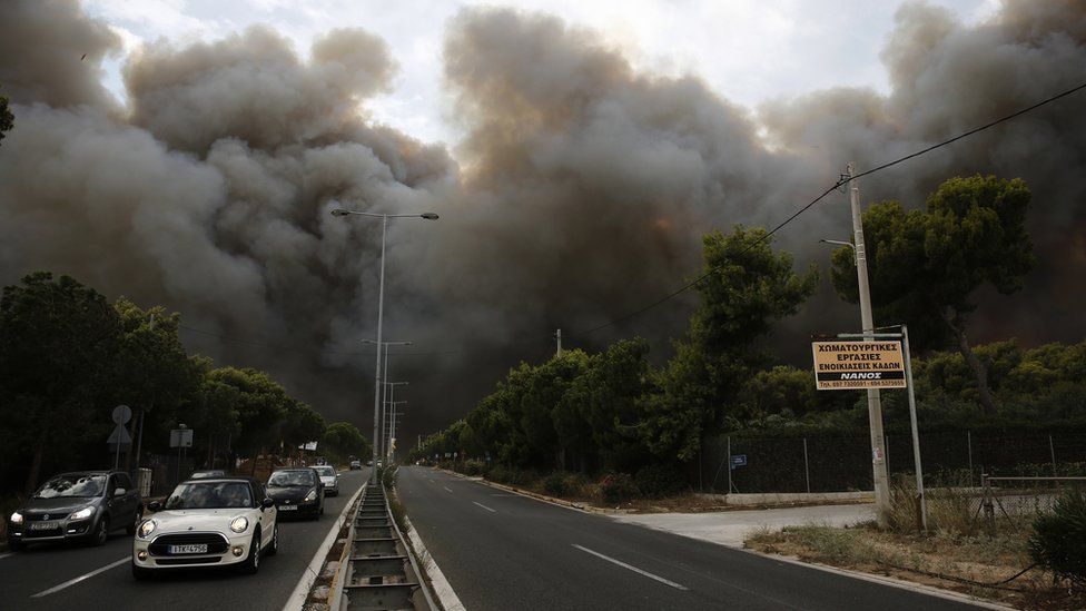 Smoke rise over an avenue during a forest fire in Neo Voutsa, a north-eastern suburb of Athens, Greece, 23 July 2018.