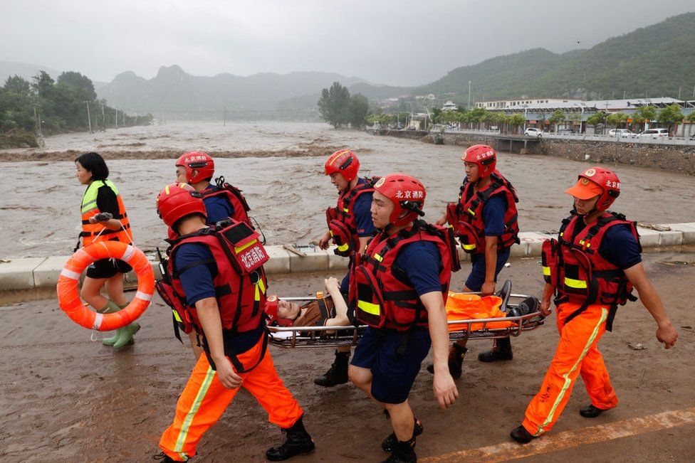 Firefighters use a stretcher to transfer an elderly man from Shuiyuzui Village in flood-hit Mentougou District on August 1, 2023 in Beijing, China.