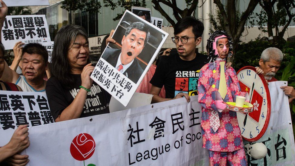 Leung Kwok-hung - known as "Long Hair" - of the League of Social Democrats holds a placard of Hong Kong Chief Executive Leung Chun-ying as they attend a rally in Hong Kong on July 1, 2016