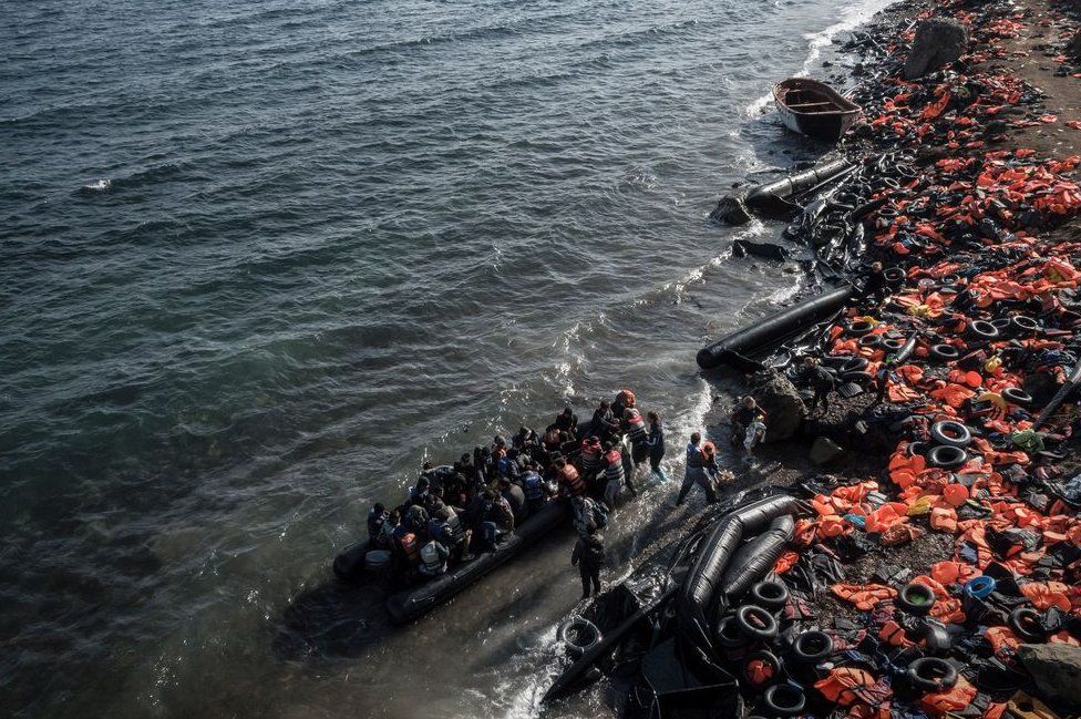 Life jackets abandoned on beach as another dinghy of people reaches shore