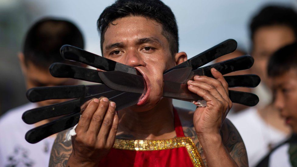 Devotee with several knives piercing his cheeks