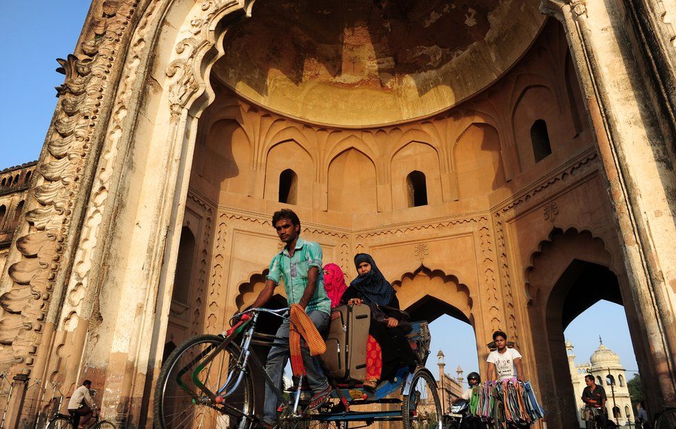 An Indian rickshaw driver transports passengers past the Rumi Darwaza in Lucknow