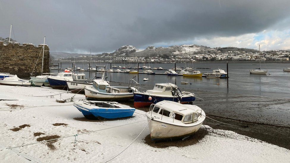 Snow at a harbour in Conwy with boats