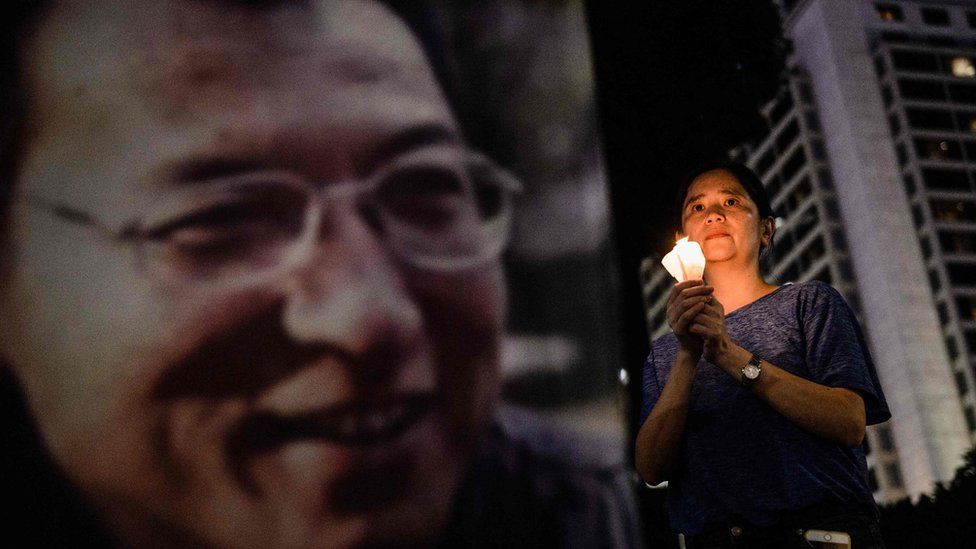 A woman holds a candle as she attends a vigil for terminally-ill Nobel laureate Liu Xiaobo (pictured on banner) in Hong Kong on June 29, 2017
