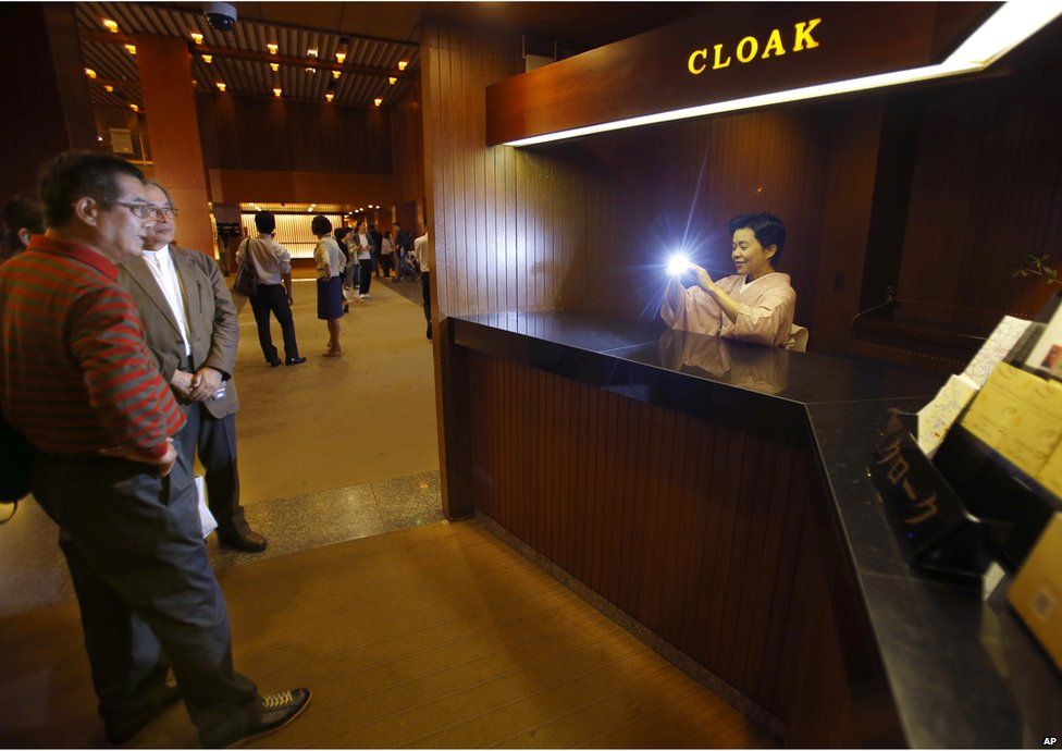 An employee takes a photo of visitors at the main lobby of Hotel Okura in Tokyo, Monday, 31 August 2015.