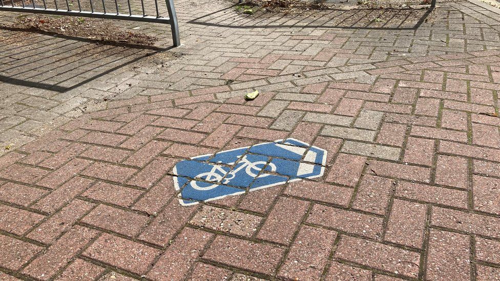 Blue cycling sign pointing off pavement
