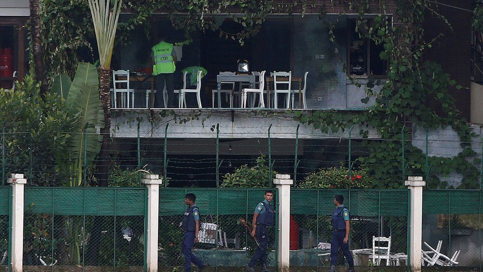 Policemen patrol outside the Holey Artisan Bakery and the O"Kitchen Restaurant as others inspect the site after gunmen attacked, in Dhaka, Bangladesh, July 3, 2016.