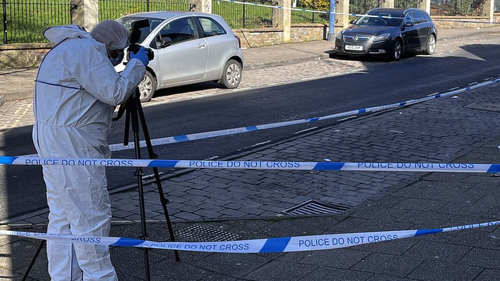 Police forensic teams photograph a street within a police tape cordon in Bristol