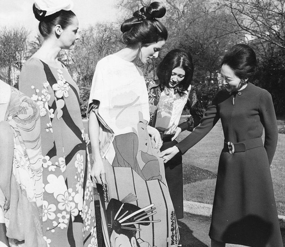 Мадам Юкава (справа), жена посла Японии, разговаривает с дизайнером Ханаэ Мори и группой моделей во время частного показа мод в саду посольства Японии, Лондон, 2 марта 1972 г.