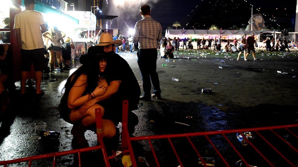 A couple, wearing country music hats, cower together at the scene of a shooting at musical festival
