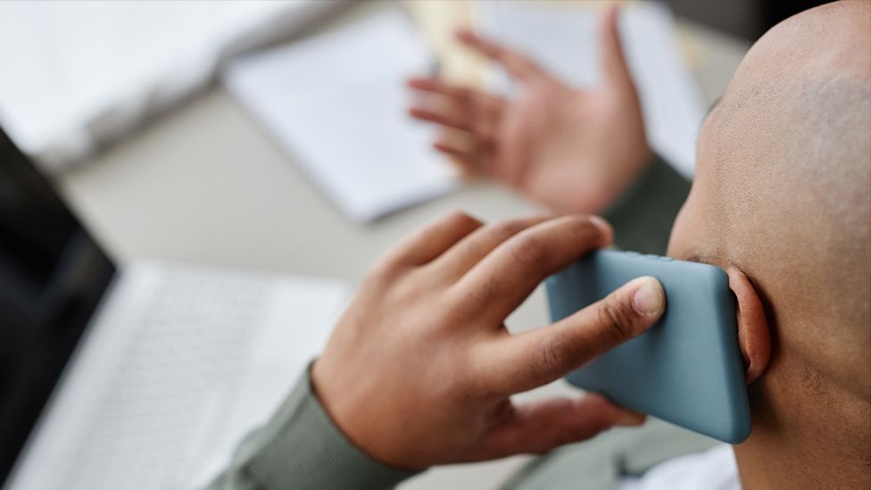 A stock image of a man talking on his mobile phone whilst at work