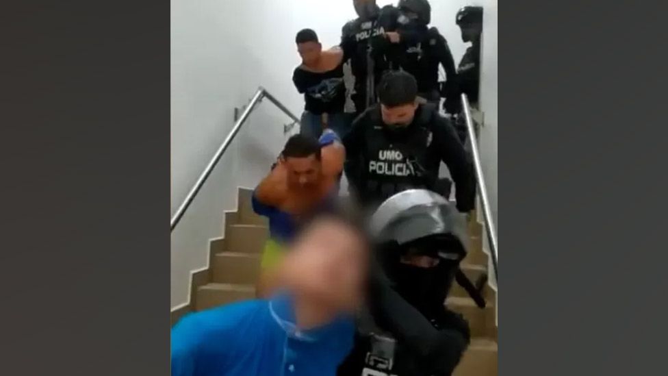 Полиция выводит мужчин из больницы после их ареста.