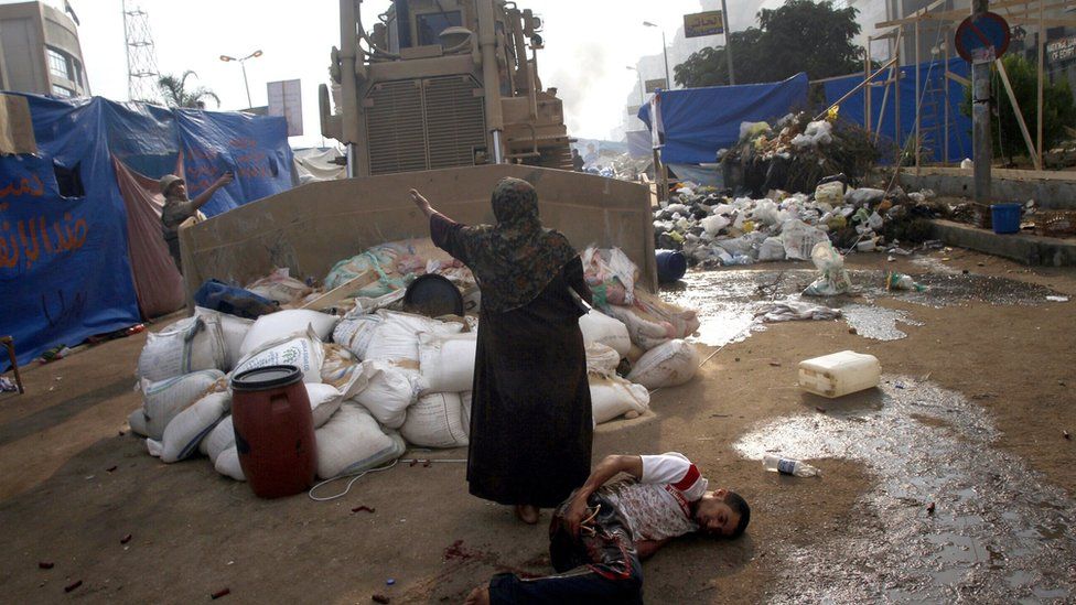 An Egyptian woman tries to stop a military bulldozer from running over a wounded youth during clashes in Cairo's Rabaa al-Adawiya (14 August 2013)