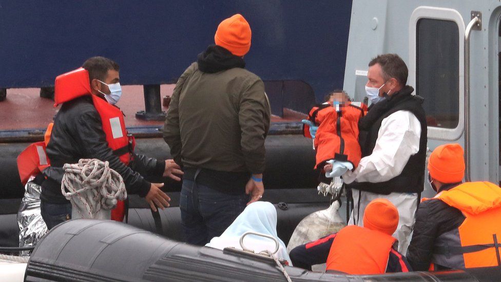 A small child is lifted off a Border Force vessel at the port of Dover