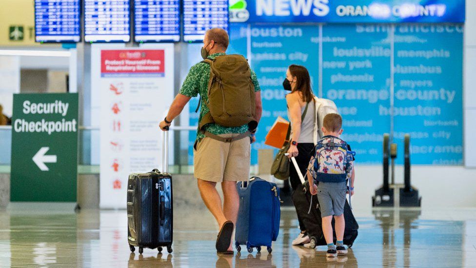 Семья направляется на проверку безопасности в аэропорту Джона Уэйна в Санта-Ана, Калифорния, в среду, 30 июня.