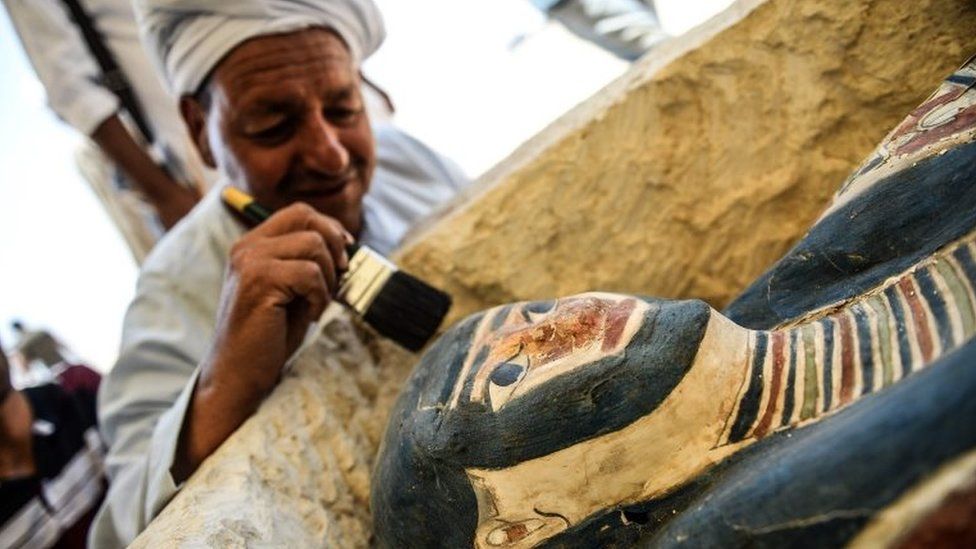 A man brushes off dust from a sarcophagus, part of a new discovery carried out near the King Amenemhat II's pyramid at Dahshur. Photo: 13 July 2019