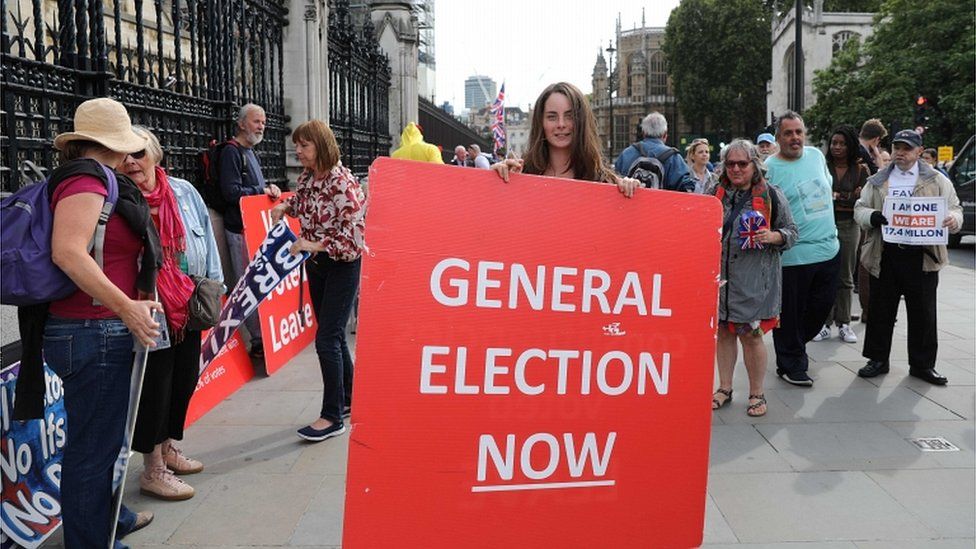 A protester in Westminster holds a placard reading 'general election now'