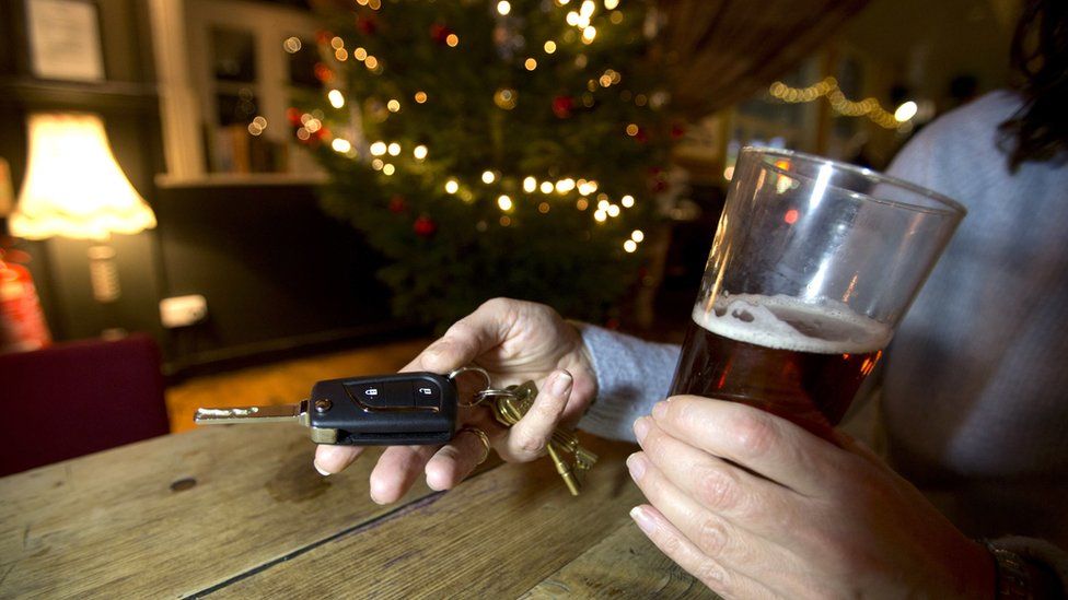 Person holding drink and car keys