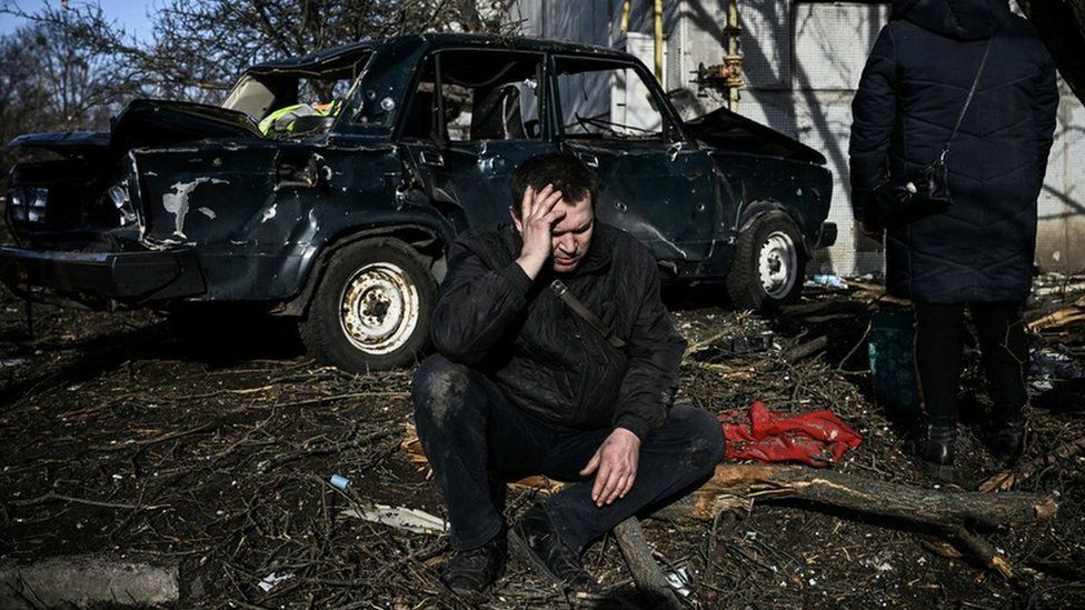 A man sits outside his destroyed building after bombings on the eastern Ukraine town of Chuhuiv on 24 February 2022