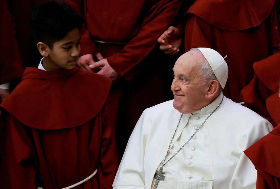 Pope Francis smiles to a young member of a choir on the day of the weekly general audience, in Paul VI hall at the Vatican, February 28, 2024.