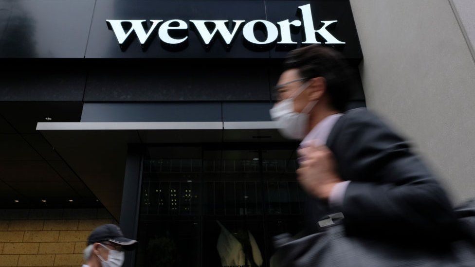 A man walks past the logo of WeWork in Tokyo on May 18, 2020.