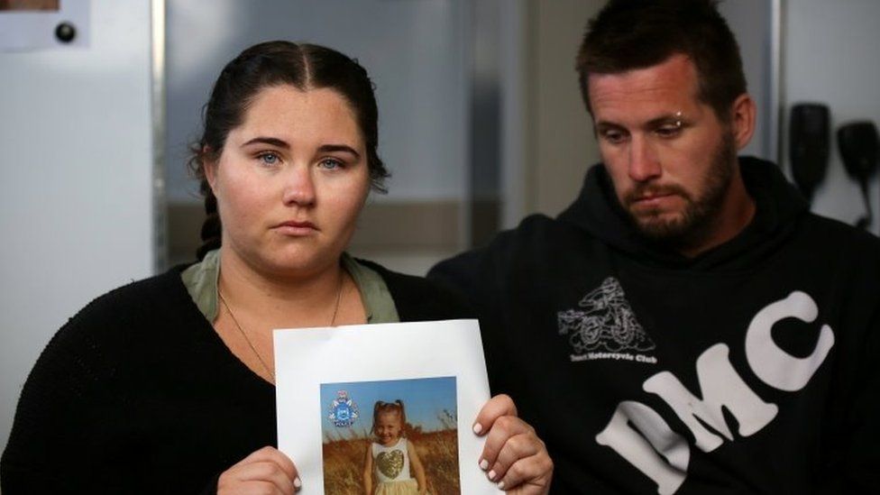 Ellie Smith holds a picture of Cleo, sitting beside partner Jake Gliddon