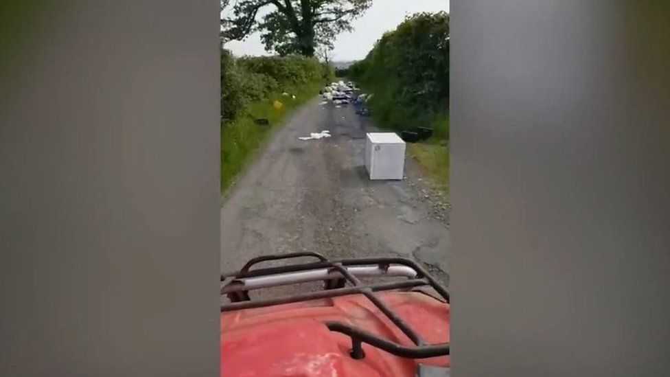 A large amount of fly-tipped items on a country road