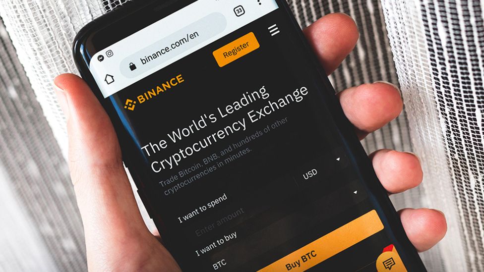 Интерфейс сайта криптовалютной биржи Binance на смартфоне в руке