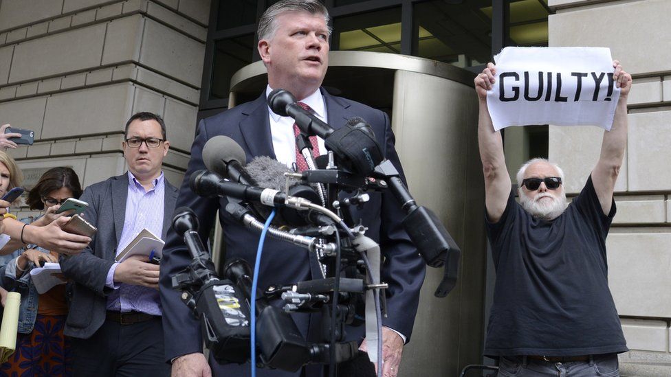 Bystander holds "guilty" sign as Kevin Downing, defence lawyer for Paul Manafort, speaks in Washington, 14 September 2018